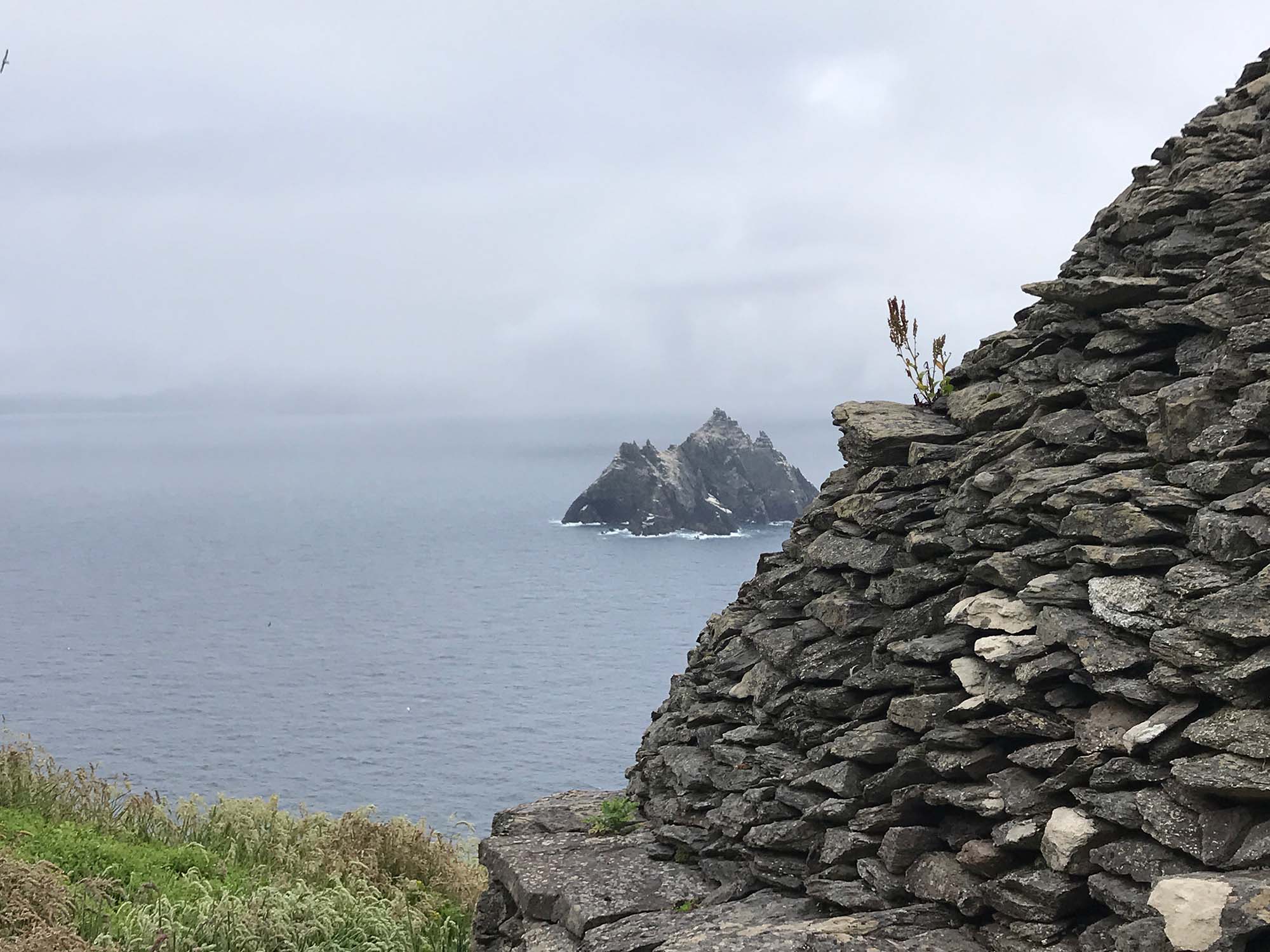 Island structure in the ocean overlooked by a cliff rock-like structure.
