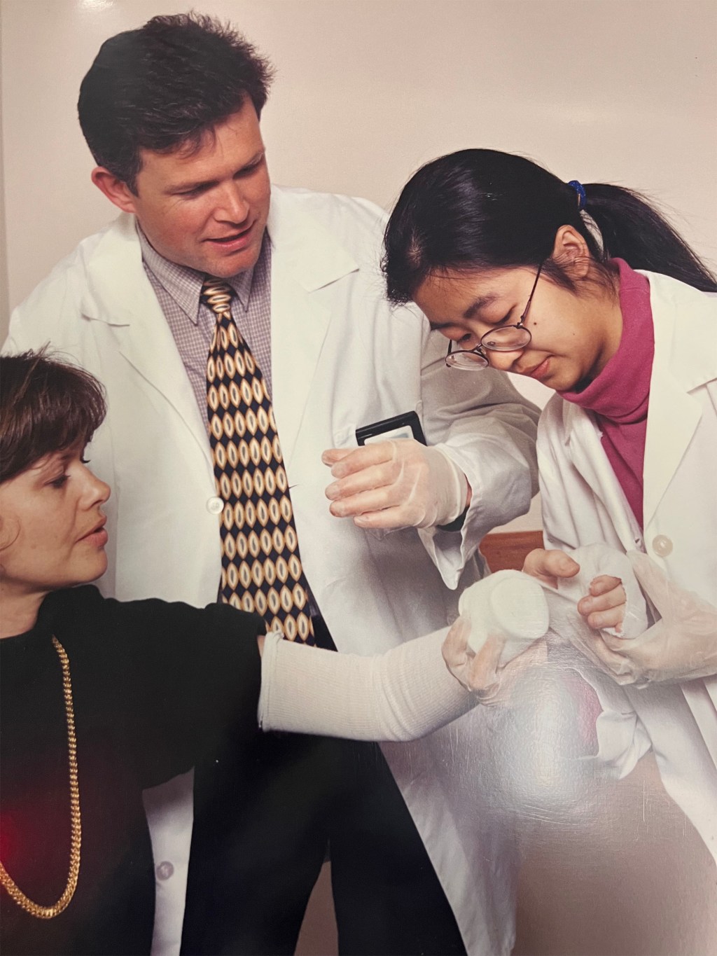 Dr. Power assisting another doctor on a medical procedure wrapping a patients injured hand with medical gauze.