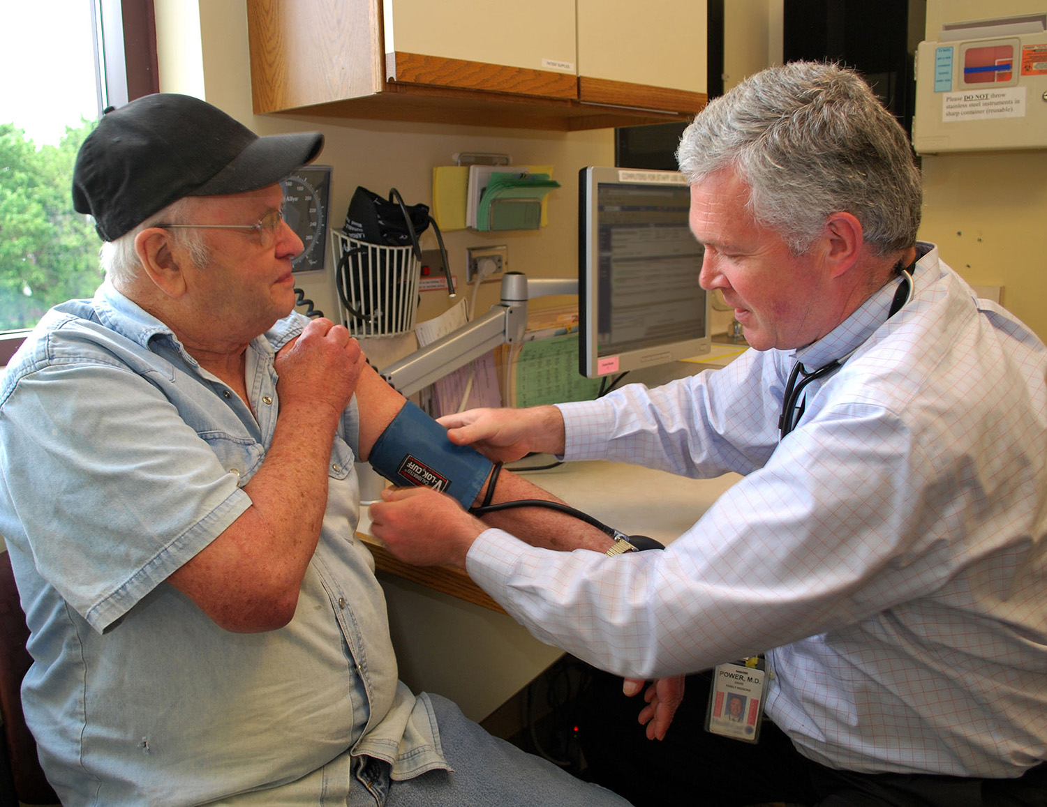 Dr. David Power taking a blood pressure reading of a patient inside of a doctor's office.