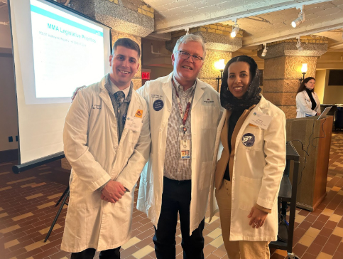 Dr. David Power with two students in front of a speaker podium and projection screen.
