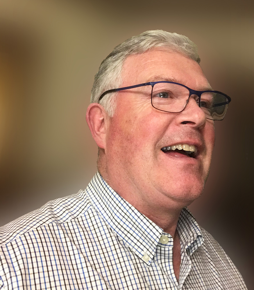 Portrait photograph of David V. Power in conversation with a blurry background.